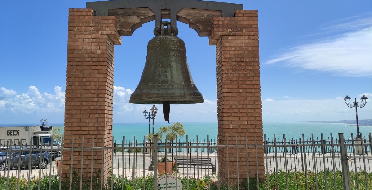 Huge bell commemorating Vasto landslide with sea beyond