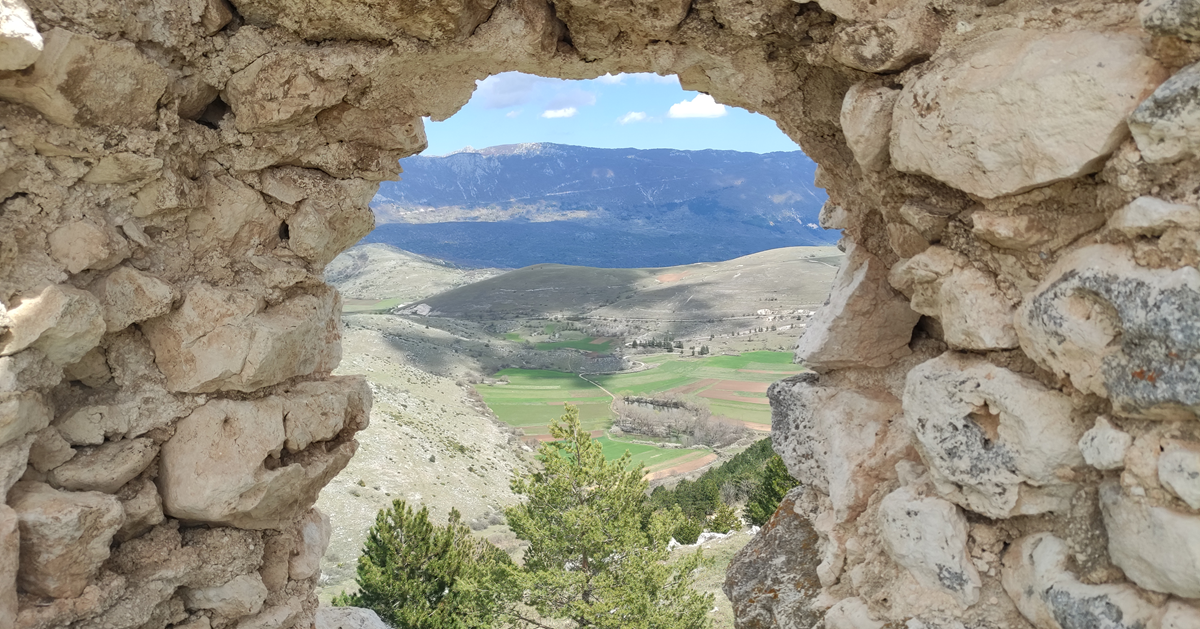 View of the valley seen through hole in ruined stone wall