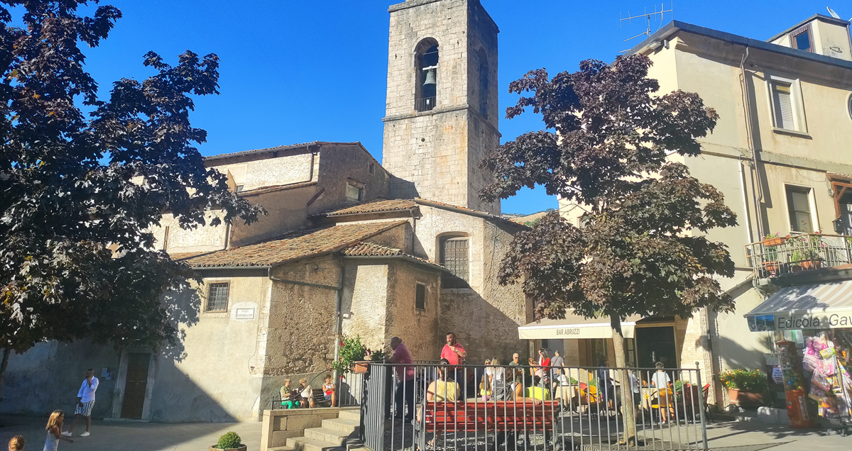 Square with people on café terrace, with houses and church  tower beyond